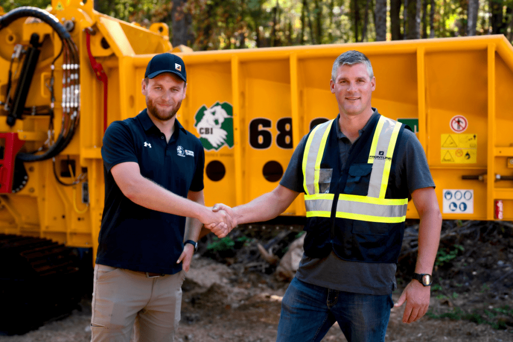 Nikolas McClelland (Regional Sales Manager for Terex, CBI, and Ecotec) shakes hands with Daryl Todd (President at Frontline Machinery) in front of a CBI Horizontal Grinder.